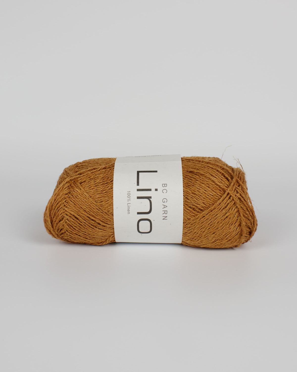 A mustard brown ball of linen yarn on a white background