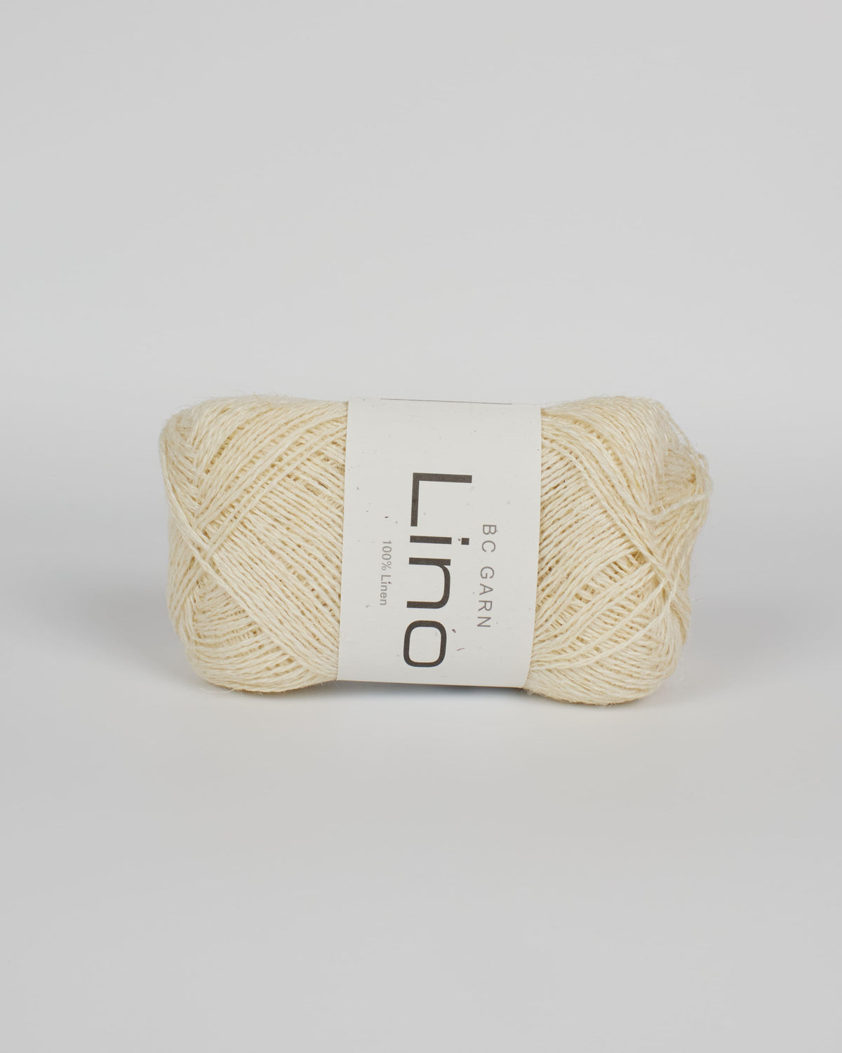 An off white ball of linen yarn on a white background