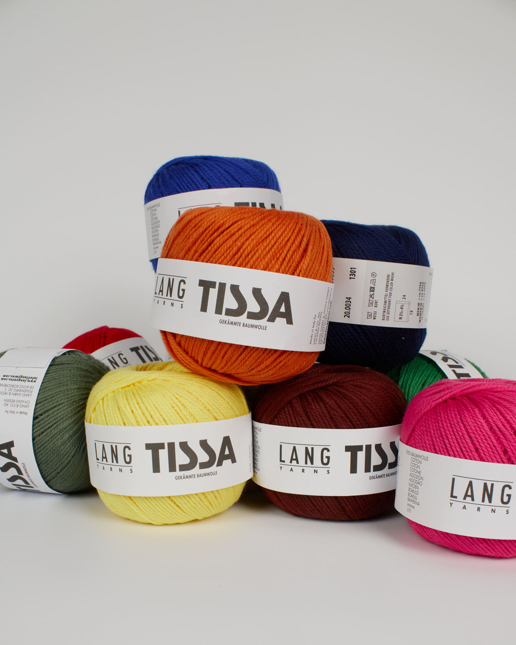 A collection of different coloured yarns stacked on top of each other on a white background